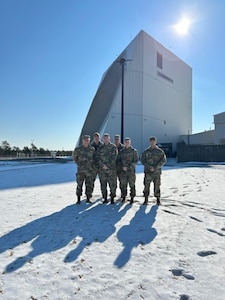 Military members stand in front of radar installation.