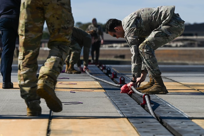 U.S. Air Force Senior Airman Toren Vanderveen, 628th Civil Engineer Squadron electrical power production journeyman, secures the arresting cable during an annual certification at Joint Base Charleston, S.C., Jan. 28, 2025. An arresting cable certification is an annual requirement for the 437th Operations Support Squadron airfield management team testing the Barrier Arresting Kit-12 arresting cable system for pilots to execute a safe emergency landing.