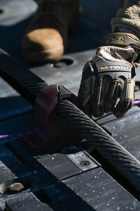 A U.S. Airmen secures an arresting cable during an annual certification at Joint Base Charleston, S.C., Jan. 28, 2025. An arresting cable certification is an annual requirement for the 437th Operations Support Squadron airfield management team testing the Barrier Arresting Kit-12 arresting cable system for pilots to execute a safe emergency landing.