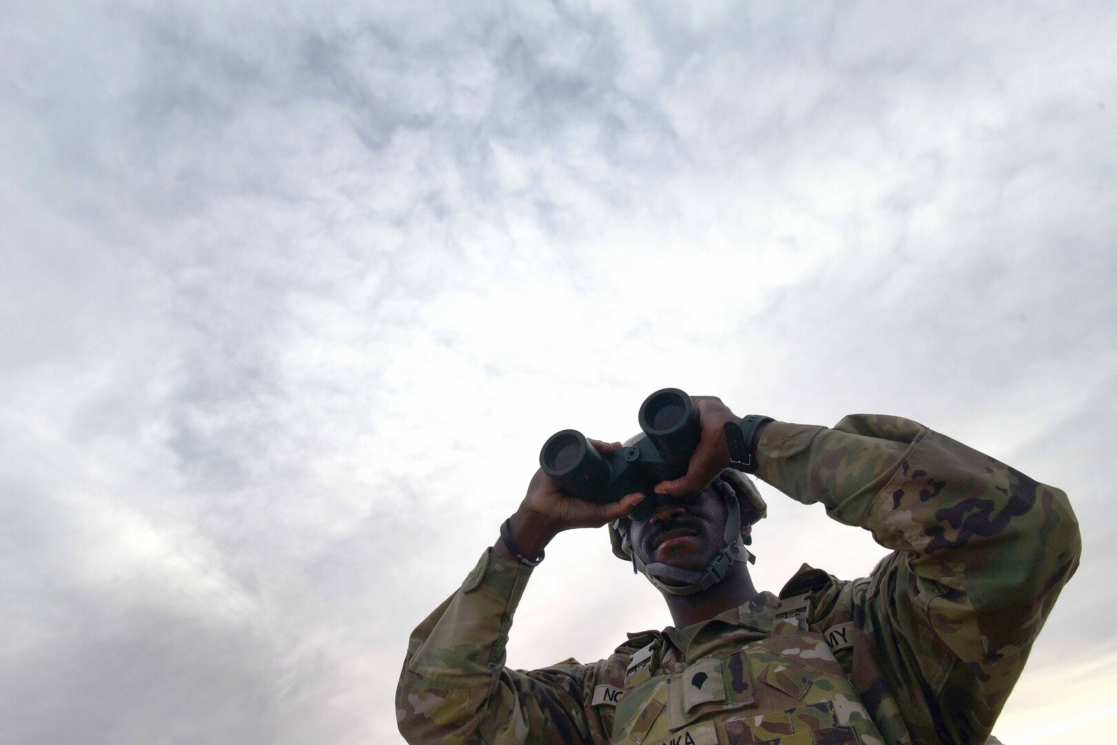 A soldier looks through binoculars.
