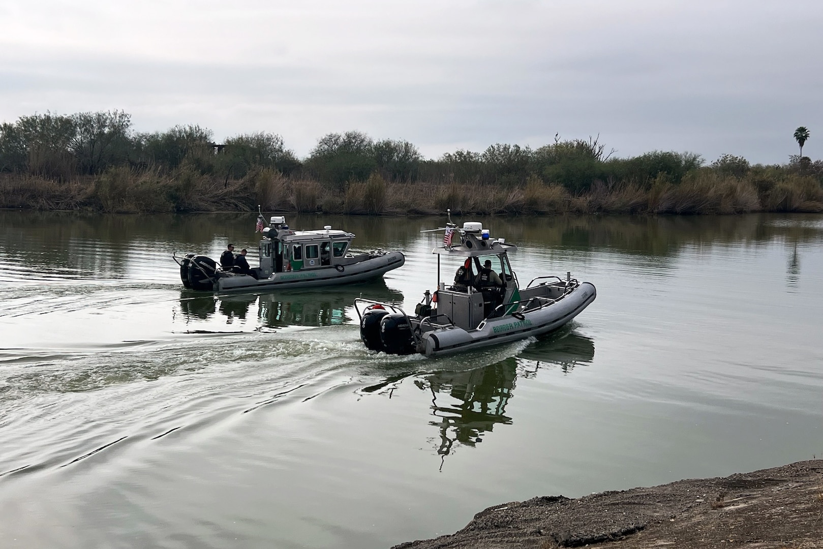 Two border patrol boats navigate a body of water.
