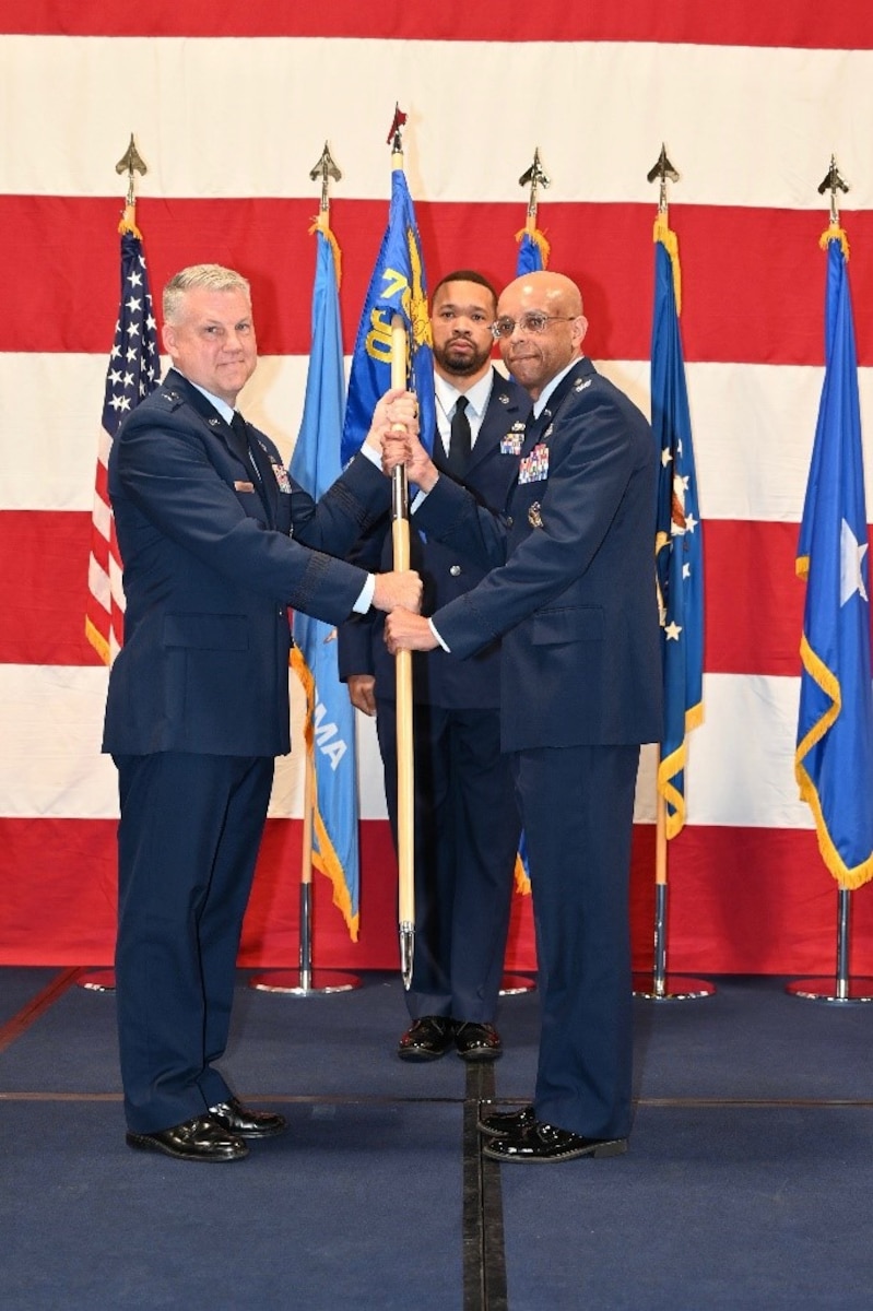 Two men on stage holding flag