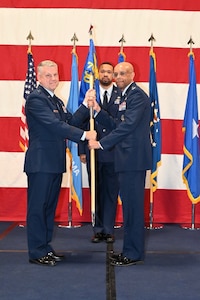 Two men on stage holding flag