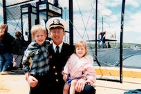 Wyatt J. Nash, Underwater Electromagnetics Stealth Advisor at Naval Surface Warfare Center Carderock Division, stands on the pier with his children after returning from his first submarine deployment in 1996. Nash is one of 10 recipients of the 2025 Assistant Secretary of the Navy (Research, Development and Acquisition) Dr. Delores M. Etter Top Scientists and Engineers of the Year Award. Carderock, the Navy's ship design and innovation powerhouse, provides the technical foundation for the future fleet through world-class research, development, and testing. (Photo courtesy of Wyatt J. Nash)