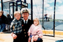 Wyatt J. Nash, Underwater Electromagnetics Stealth Advisor at Naval Surface Warfare Center Carderock Division, stands on the pier with his children after returning from his first submarine deployment in 1996. Nash is one of 10 recipients of the 2025 Assistant Secretary of the Navy (Research, Development and Acquisition) Dr. Delores M. Etter Top Scientists and Engineers of the Year Award. Carderock, the Navy's ship design and innovation powerhouse, provides the technical foundation for the future fleet through world-class research, development, and testing. (Photo courtesy of Wyatt J. Nash)