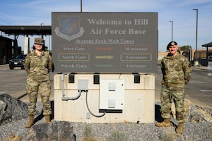 Senior Airman Jenna Skinner (left), 75th Communications and Information Directorate, and Tech. Sgt. Kyle Williamson, 75th Security Forces Squadron, stand next to the West Gate marquee which displays wait times at each of Hill's access points. The information is a result of an innovative project that captures data from the Utah Department of Transportation. (U.S. Air Force photo by R. Nial Bradshaw)