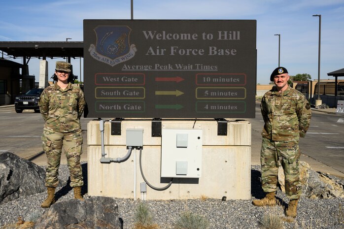 Senior Airman Jenna Skinner (left), 75th Communications and Information Directorate, and Tech. Sgt. Kyle Williamson, 75th Security Forces Squadron, stand next to the West Gate marquee which displays wait times at each of Hill's access points. The information is a result of an innovative project that captures data from the Utah Department of Transportation. (U.S. Air Force photo by R. Nial Bradshaw)
