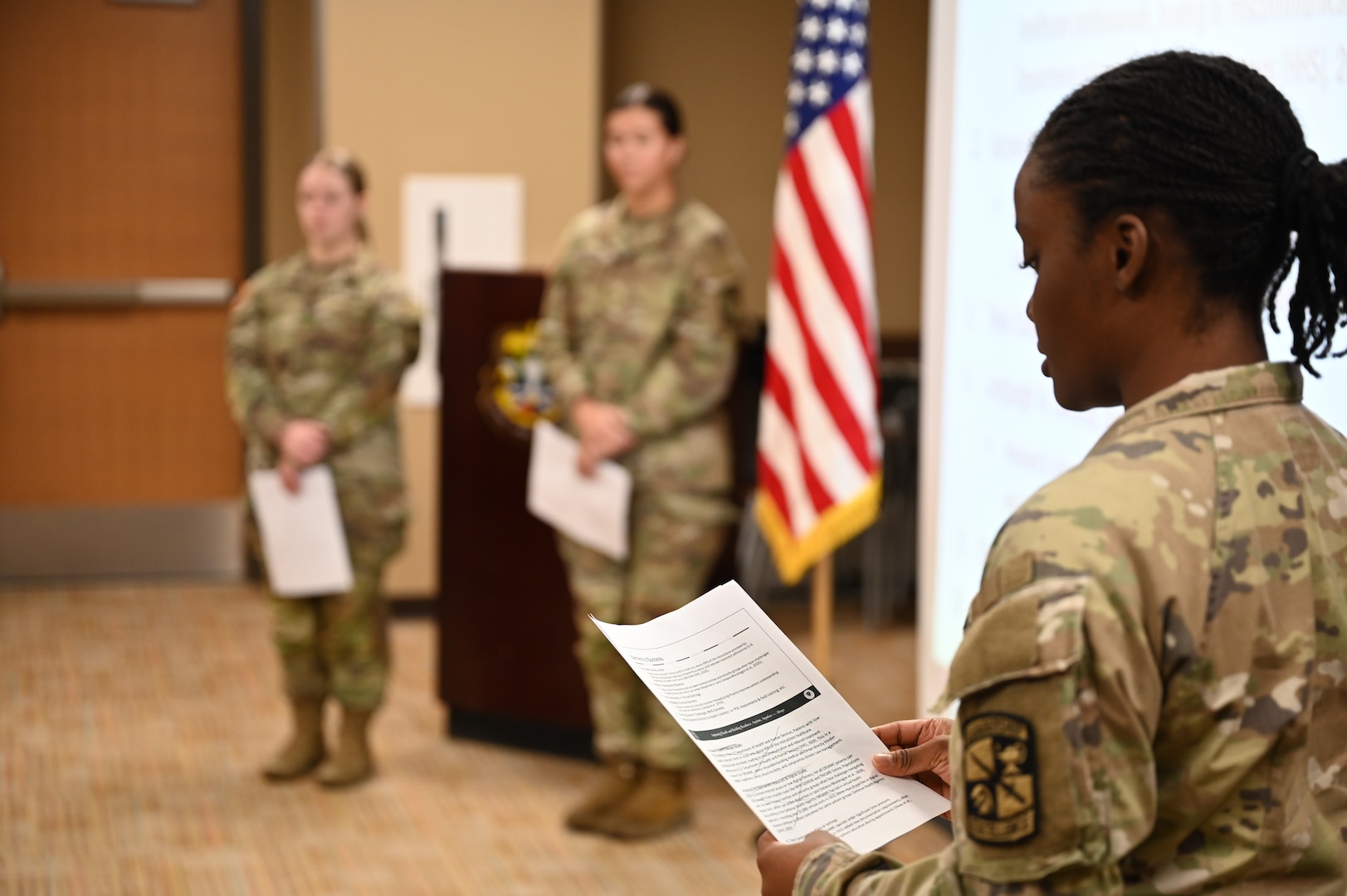 Cadets look on as Cadet Chinelo Mogbo presents her portion of the group's educational project. Cadets are required to complete a research project as part of the program.