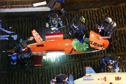 Divers and team members from Virginia Tech make in-water adjustments to their submarine, Exlienni, during a race cycle at the 18th International Submarine Races (ISR 18), hosted at Naval Surface Warfare Center, Carderock Division, from June 23-27, 2025. Carderock, the Navy's ship design and innovation powerhouse, provides the technical foundation for the future fleet through world-class research, development, and testing. (U.S. Navy photo by Kristin Behrle)