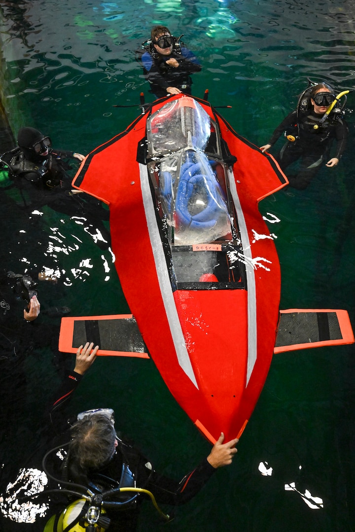 Support divers guide Javelin 2.0 into position at the start of a race. The carbon fiber and foam core vessel were built in the Barone family’s garage and piloted by 16-year-old Quinn Barone. Carderock, the Navy's ship design and innovation powerhouse, provides the technical foundation for the future fleet through world-class research, development, and testing. (U.S. Navy photo by Devin Pisner)