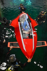 Support divers guide Javelin 2.0 into position at the start of a race. The carbon fiber and foam core vessel were built in the Barone family’s garage and piloted by 16-year-old Quinn Barone. Carderock, the Navy's ship design and innovation powerhouse, provides the technical foundation for the future fleet through world-class research, development, and testing. (U.S. Navy photo by Devin Pisner)