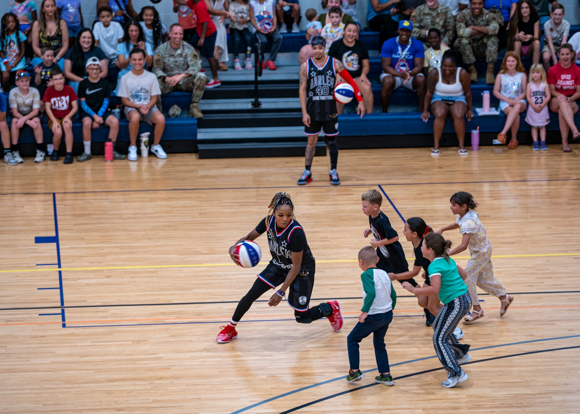 Harlem Globetrotter “Ace” Porter plays basketball with young participants at Moody Air Force Base, Georgia, June 26, 2025. Known for their flashy passes and signature moves, the team puts on a show that’s equal parts sport and spectacle. (U.S. Air Force photo by Senior Airman Leonid Soubbotine)