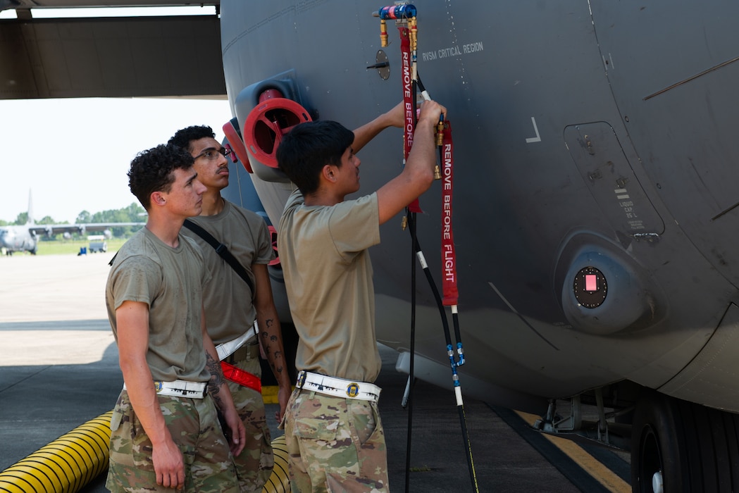 Group of airmen working on a plane outside.