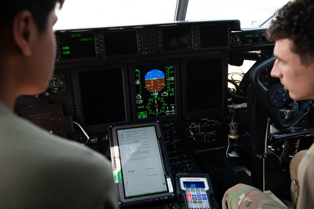 Two people looks at a monitor on a plane.