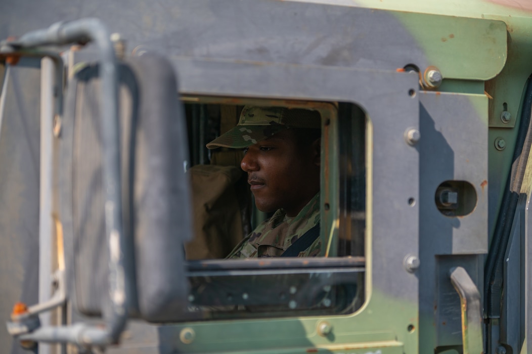 A young man in a United States Air Force uniform sits behind the wheel of a vehicle.