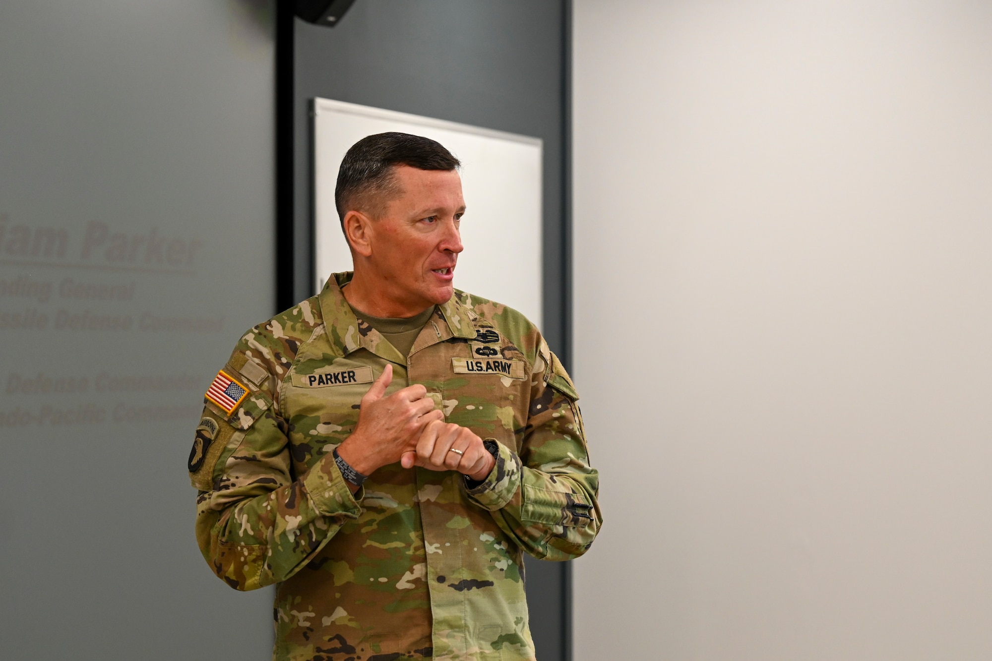 An older man in military uniform counts off on his fingers as he speaks to a crowd