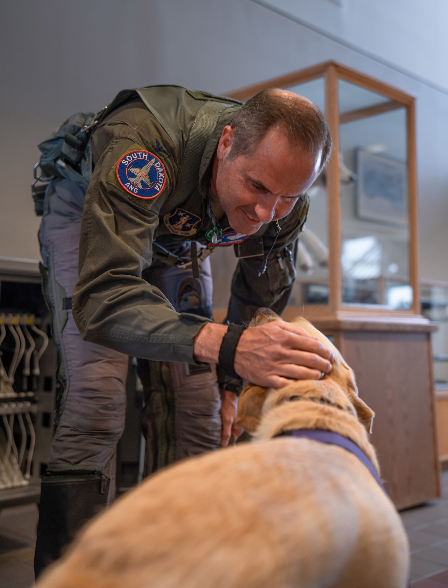 Captain, facility therapy dog, 114th Fighter Wing, greets Col. Jon Friedman, deputy commander, 114th Fighter Wing, as he prepares to fly June 24, 2025, at Joe Foss Field, South Dakota.