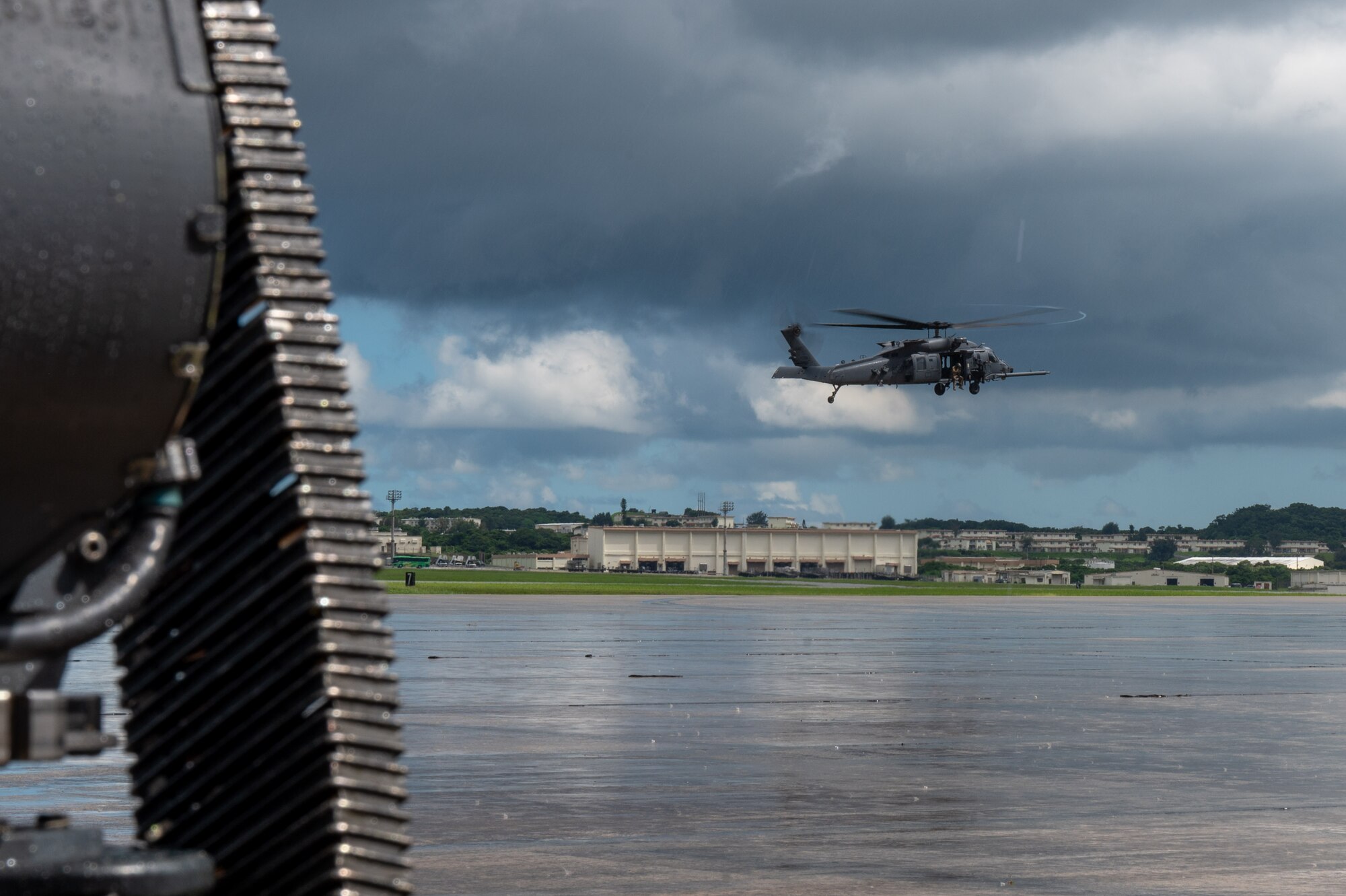 a helicopter hovers above the flightline while it rains