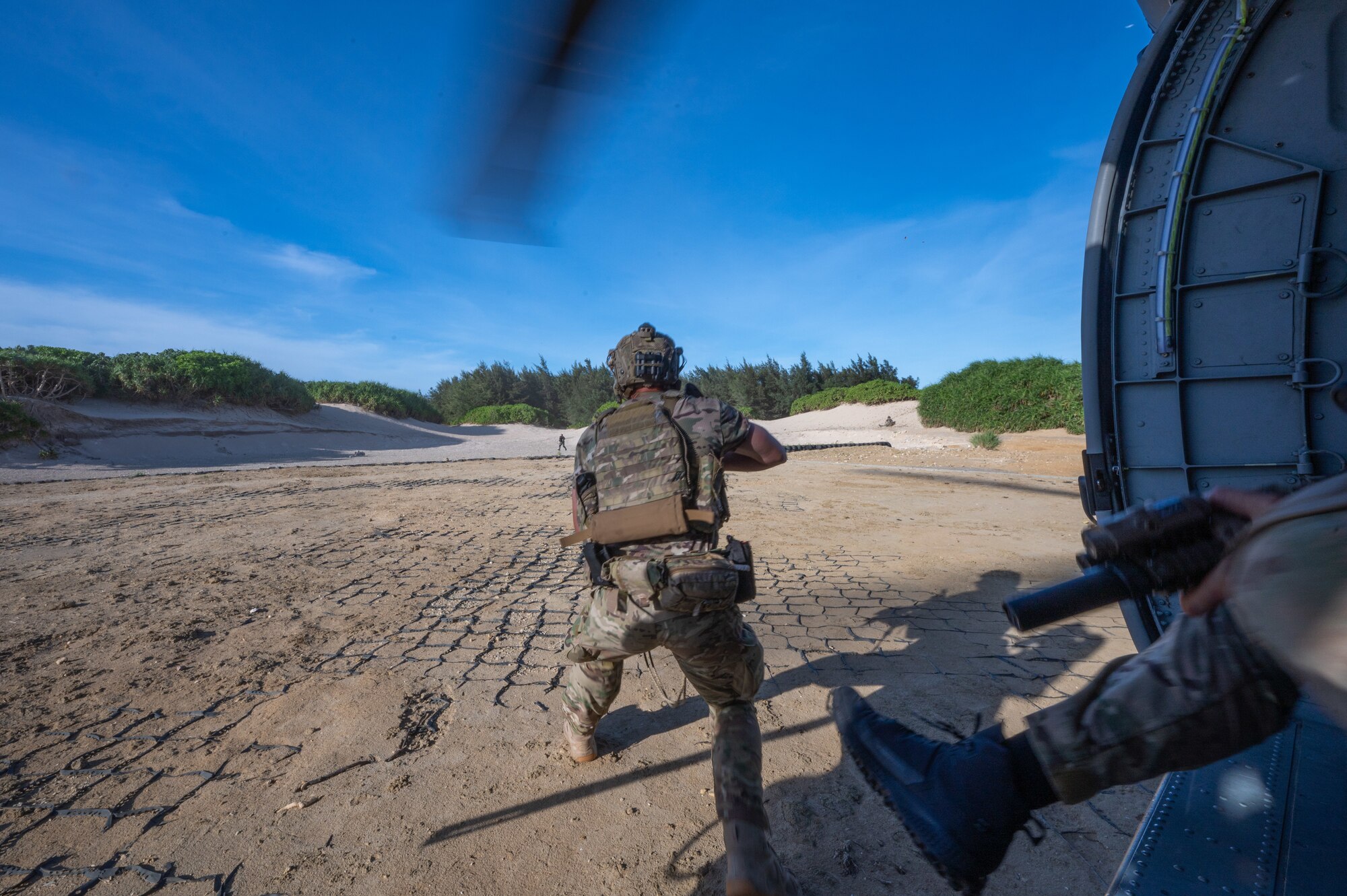 back view of a military member running out of a helicopter