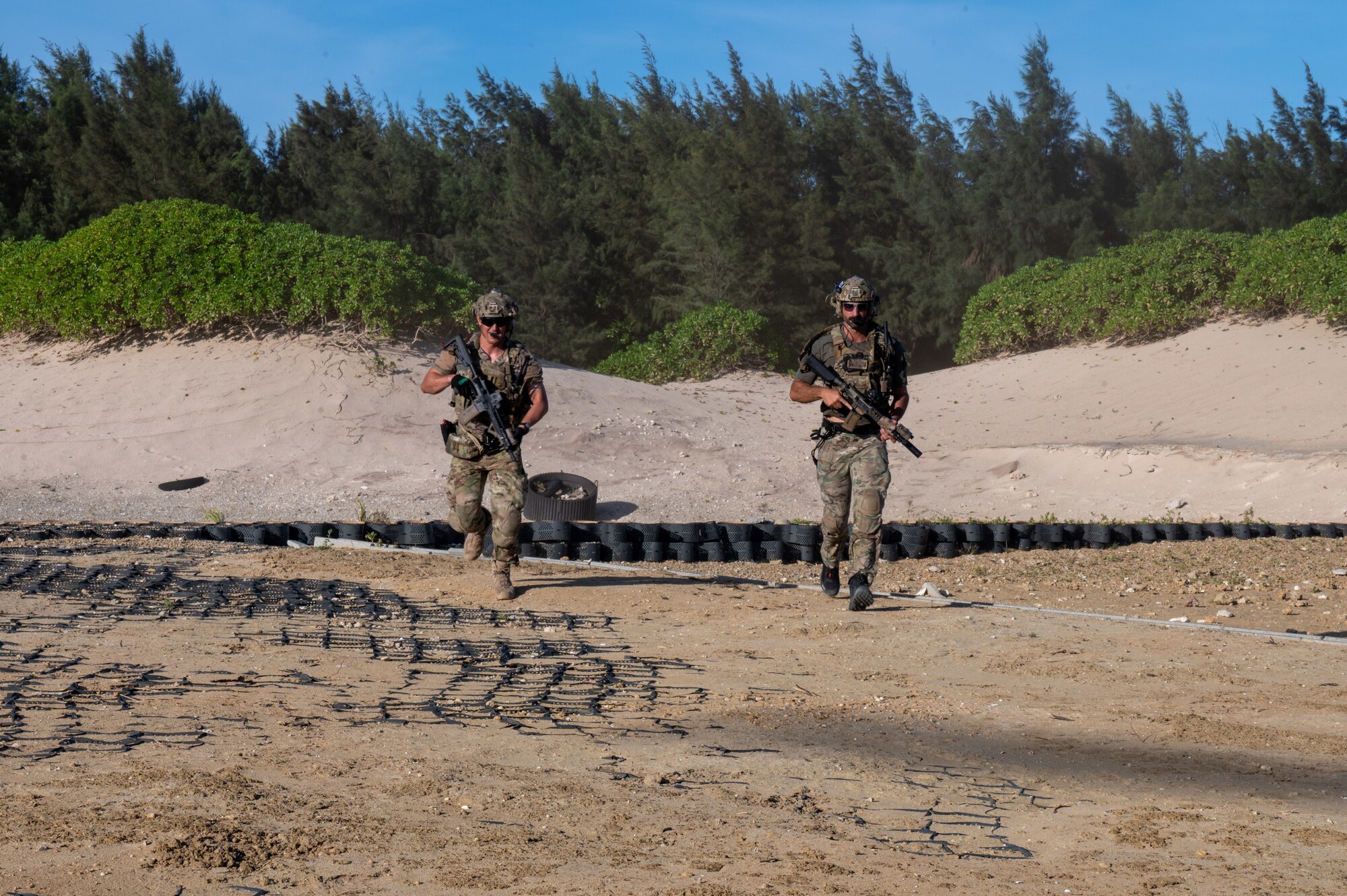 Two military members run towards a helicopter
