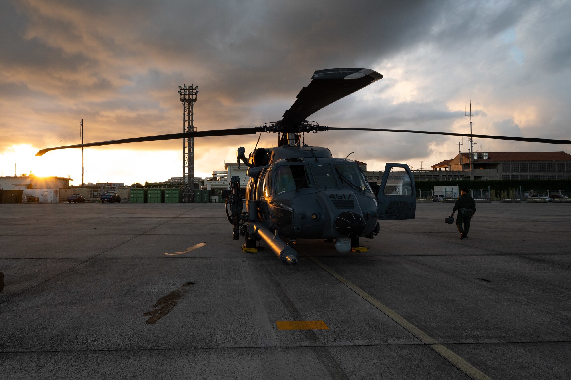A helicopter sits on the flightline during a sunset