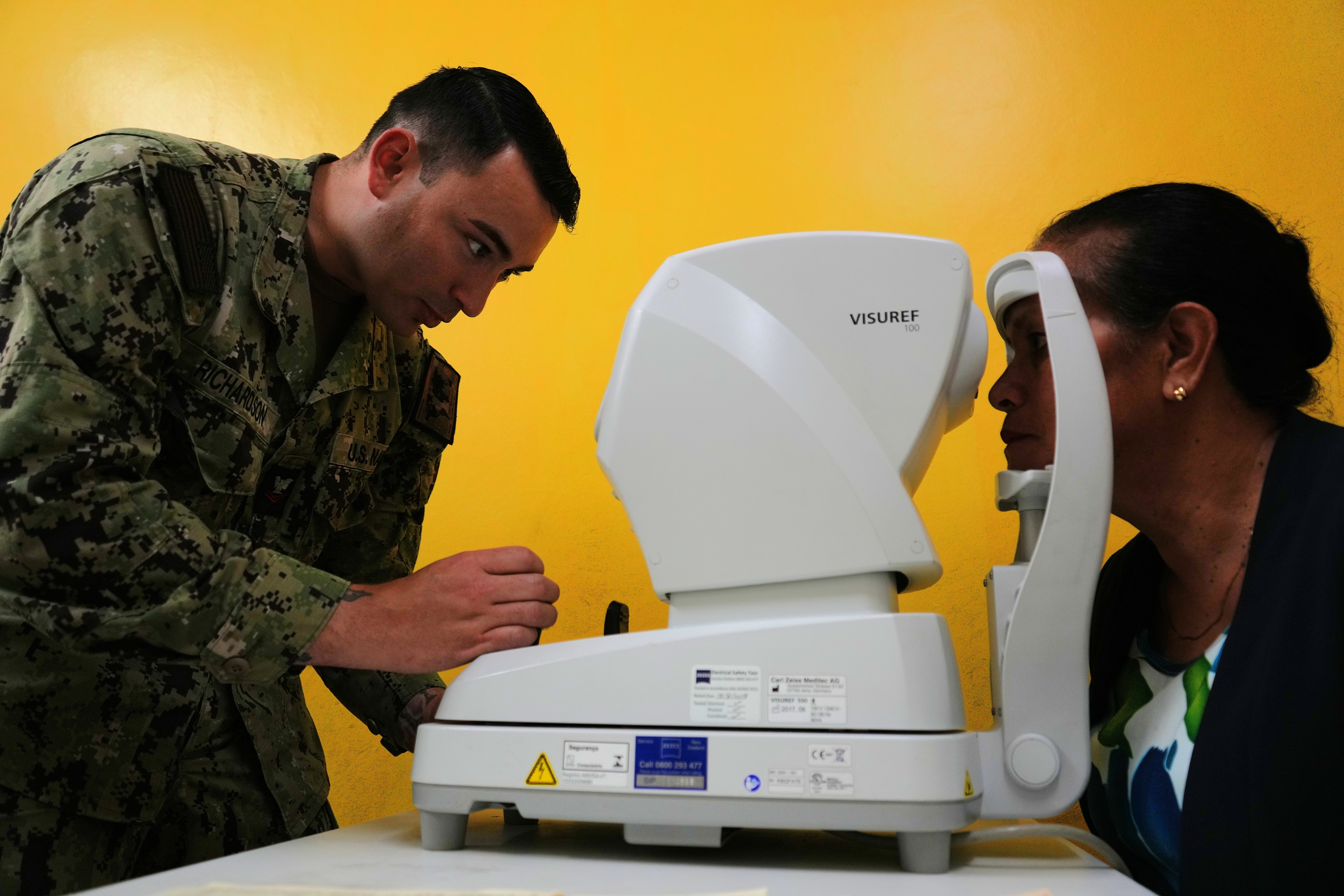 U.S. Navy Hospital Corpsman 2nd Class Brandon Richardson, left, optometry technician deployed in support of Pacific Partnership 2025 (PP-25), uses an autorefractor to check the eye pressure of a local patient’s eyes during PP-25 in Nuku’Alofa, Tonga, June 23, 2025.
