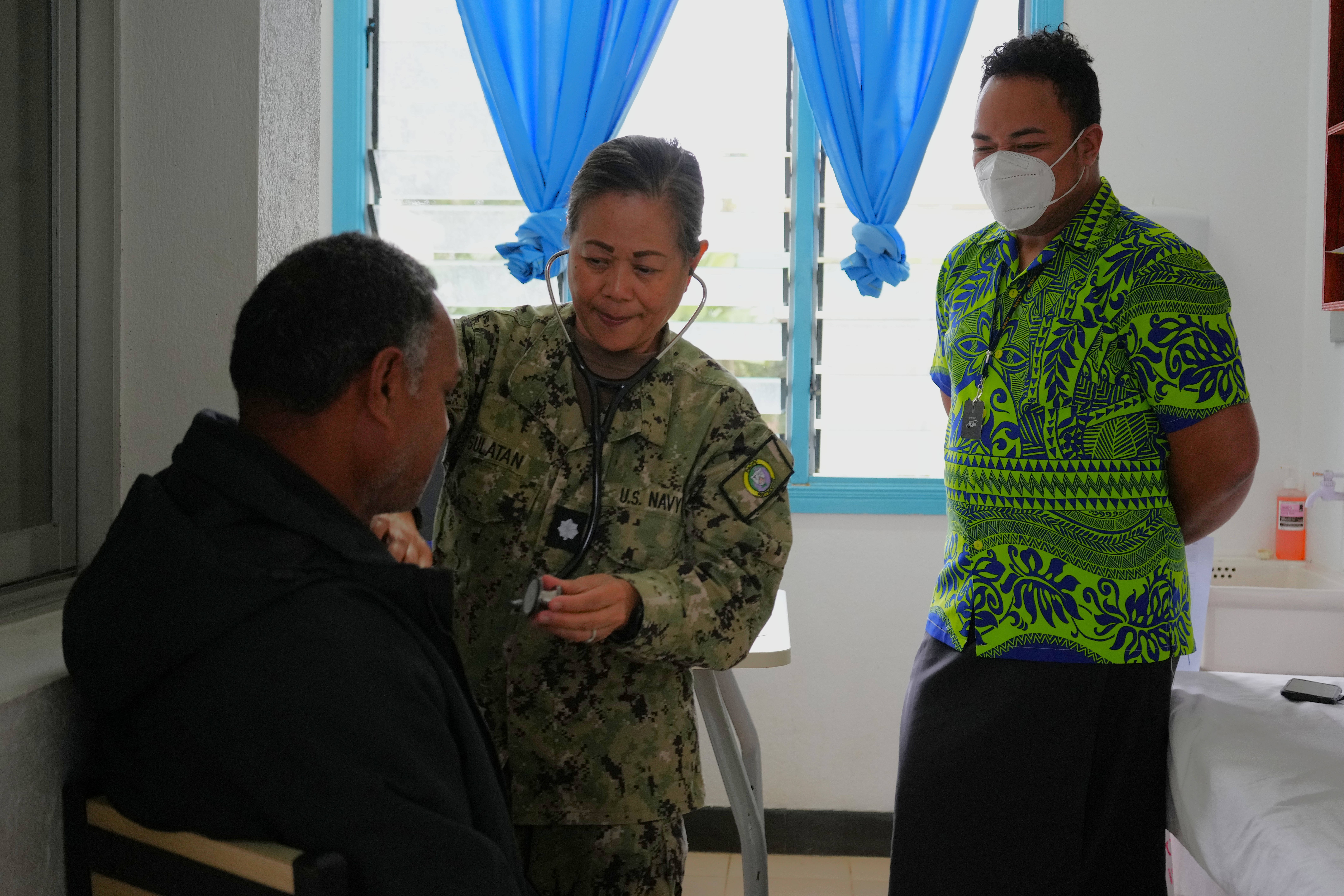 U.S. Navy Cmdr. Shirleen Sulatan, center, Nurse Practitioner deployed in support of Pacific Partnership 2025 (PP-25), assists a local patient during a health consultation at Mu’a Health Centre as part of PP-25 in Nuku’Alofa, Tonga, June 24, 2025.
