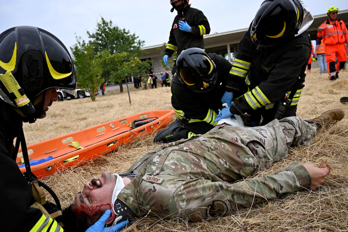 Italian firefighters assist a simulated injured personnel laying on the ground