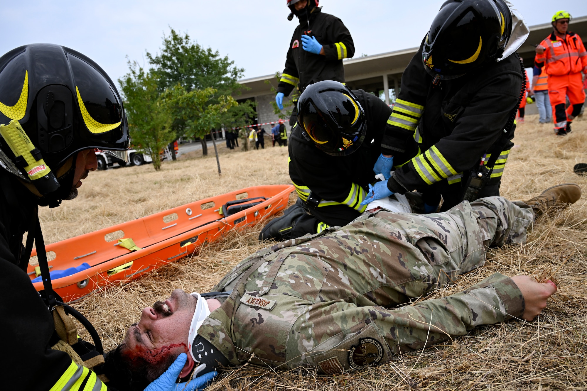 Italian firefighters assist a simulated injured personnel laying on the ground