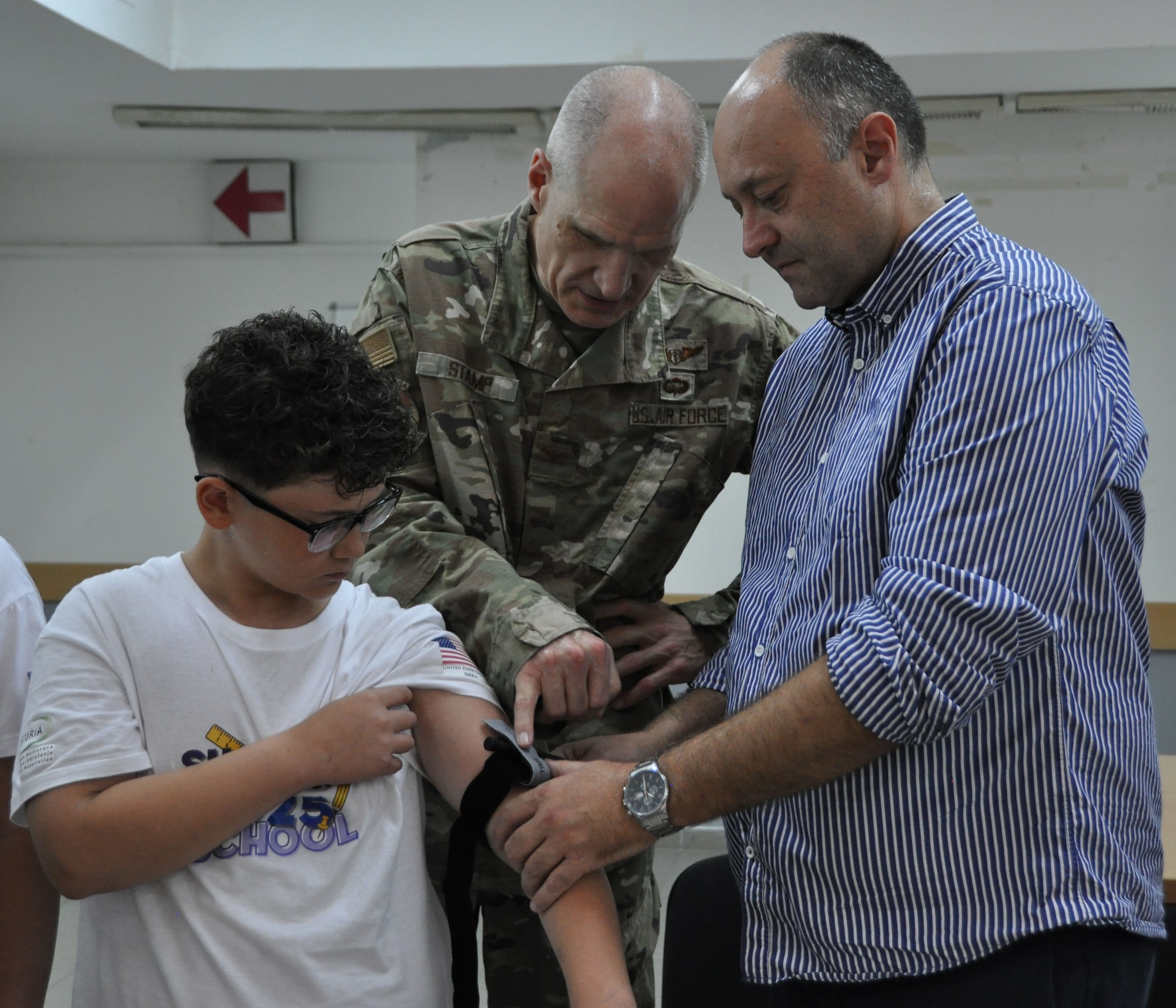 Two men applying a tourniquet to a boy's arm.