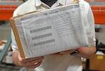 A man holds a box in a warehouse.