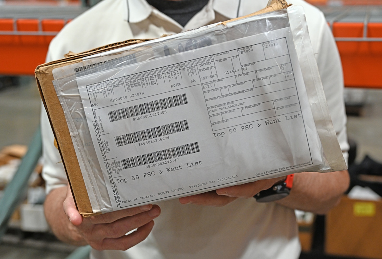 A man holds a box in a warehouse.