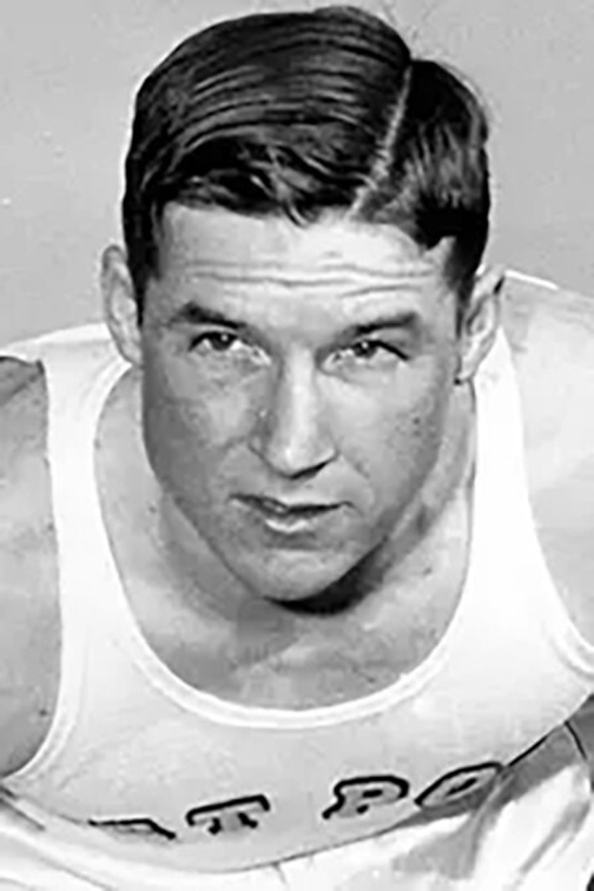 A man wearing a tank top crouches down in a running position.