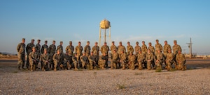 a group photo of 134th ARW civil engineers at sunrise with the Moron Air Base water tower behind them.