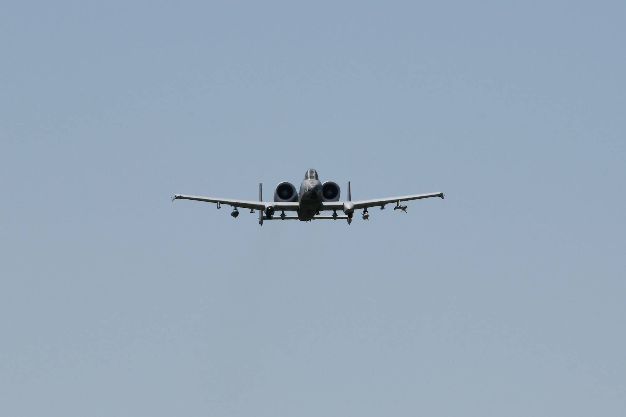 An A-10C Thunderbolt II fighter jet is seen from the front flying in the sky.