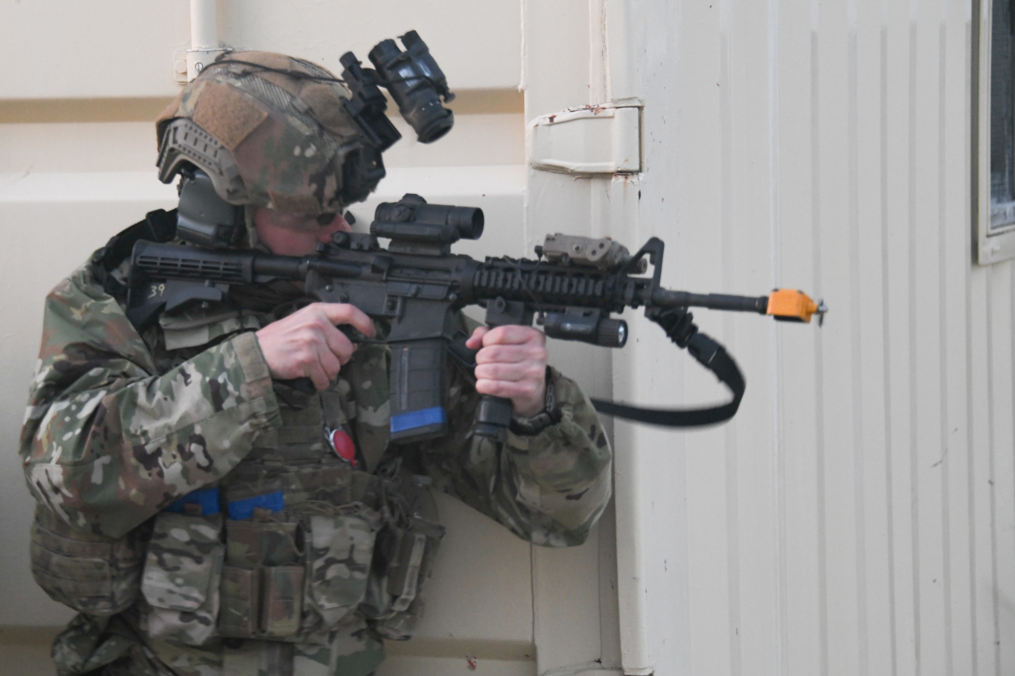 A U.S. Airman aims a rifle around a corner wall during a combat exercise.