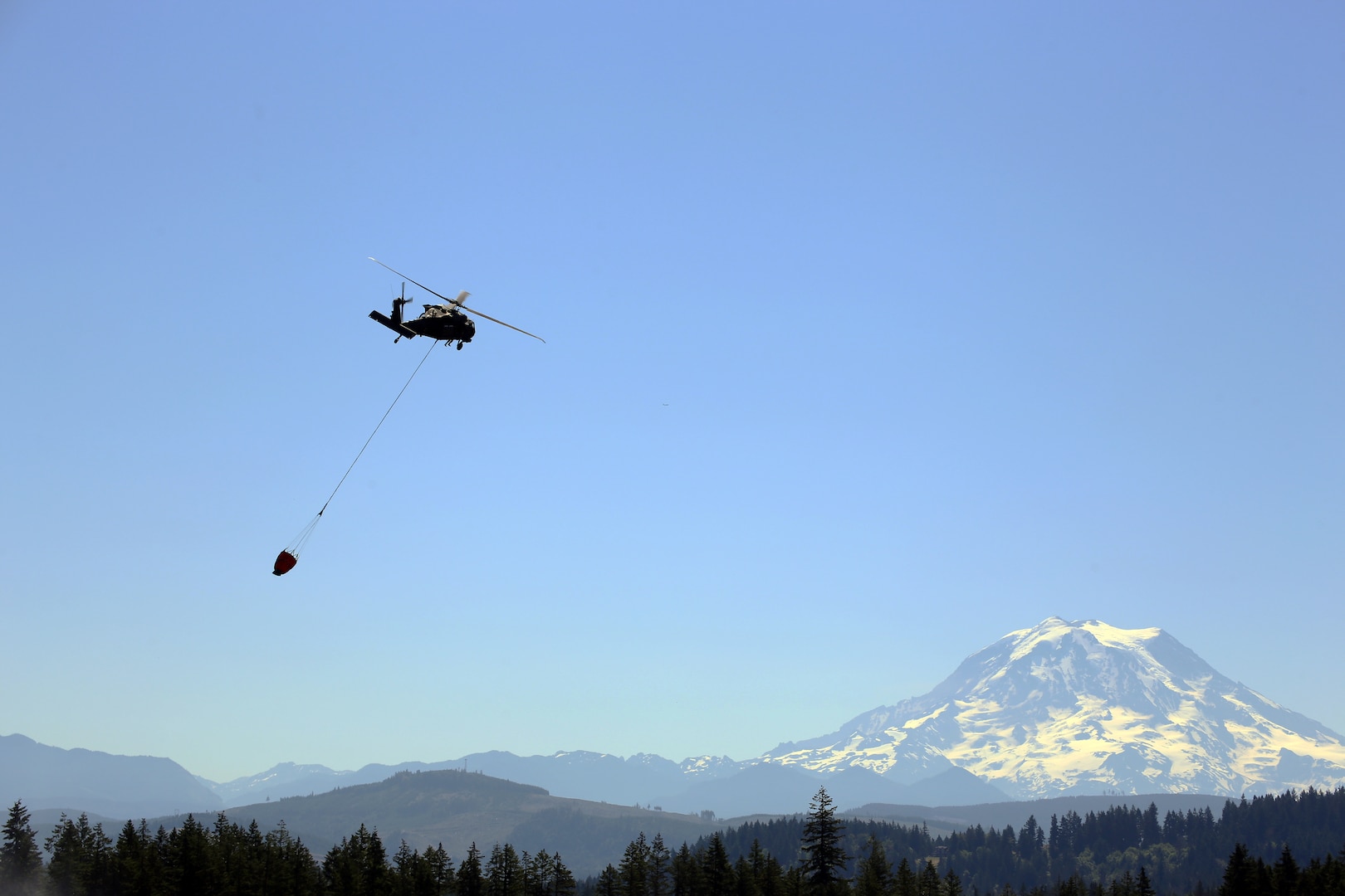 A UH-60 Blackhawk Helicopter from Charlie Company, 1st Battalion, 140th Aviation, 96th Troop Command, Washington Army National Guard conducts water bucket training with Central Pierce Fire and Rescue, June 30, 2025, near Puyallup, Wash.