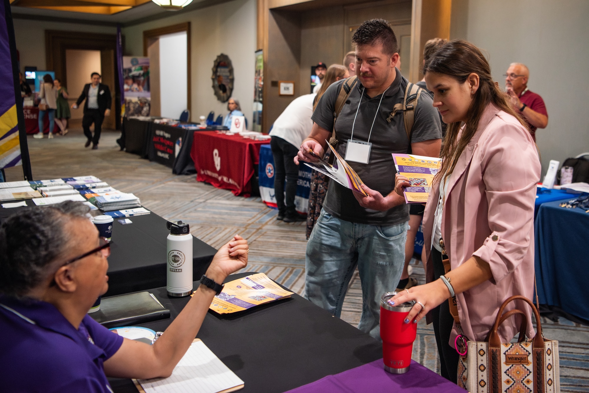 Attendees talk to a woman at a booth