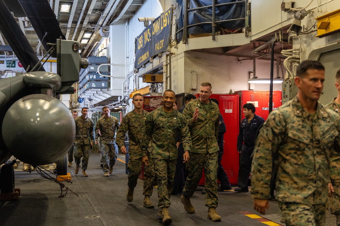U.S. Marine Corps Lieutenant General Calvert Worth Jr., middle, Commanding General, II Marine Expeditionary Force, receives a tour of the hangar bay during his visit aboard the Wasp-class amphibious assault ship USS Iwo Jima (LHD 7), during Composite Training Unit Exercise while underway in the Atlantic Ocean, June 28, 2025. During COMPTUEX, the IWO ARG and 22nd MEU(SOC), refine tactics, techniques, and procedures to execute warfighting functions that enhance operational readiness and lethality as a unified IWOARG/22MEU(SOC) team. (U.S. Marine Corps photo by Cpl. Sharon Errisuriz)