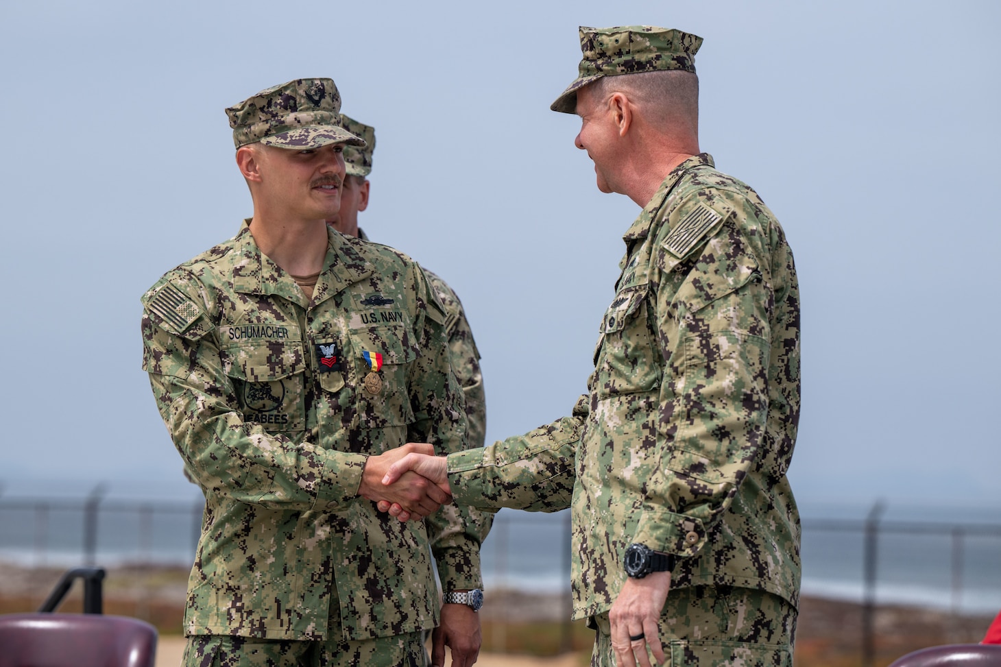 Two men shaking hands. Utilitiesman 1st Class Steven Schumacher shakes the hand of Rear Adm. Dean VanderLey, commander, Naval Facilities Engineering Systems Command, at the Silver Strand Training Complex in San Diego.