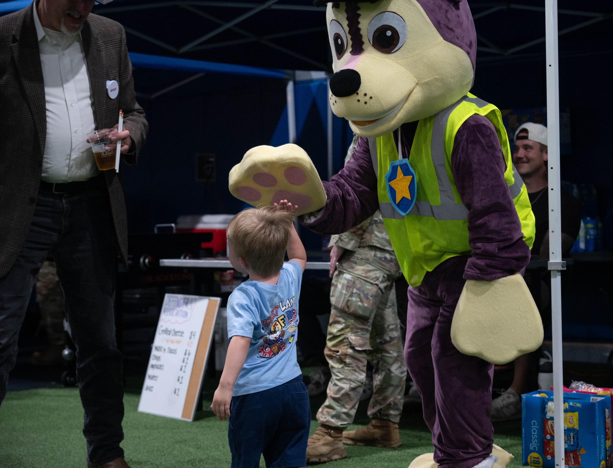 A child high-fives a mascot during Freedom Fest at Minot Air Force Base, North Dakota, June 27, 2025. Freedom Fest had music, food, games and fireworks for the Team Minot community to enjoy. (U.S. Air Force photo by Airman 1st Class Wesley Davies)