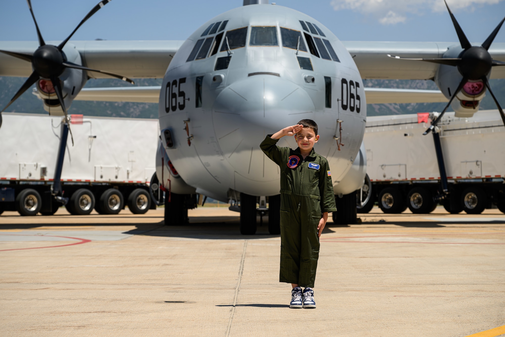 Dylan renders a salute in front of a C-130 Hercules aircraft.