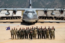 A group photo in front of a C-130 Hercules aircraft.