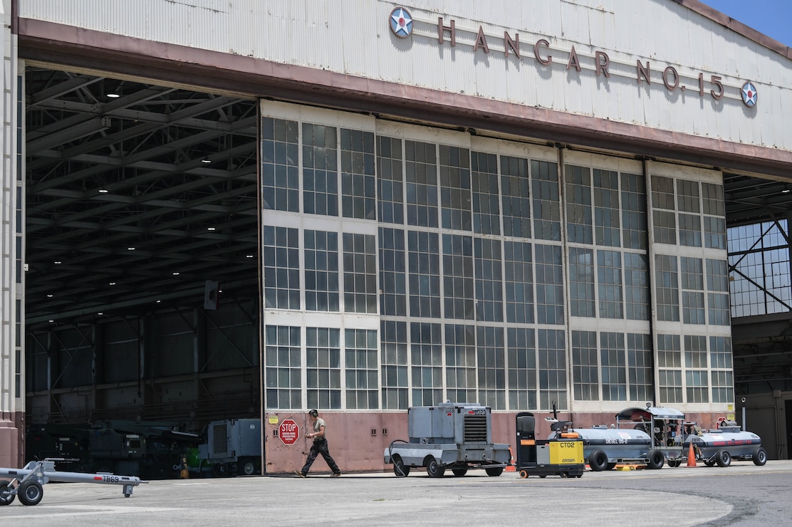 Airman walking in front of a large hangar.