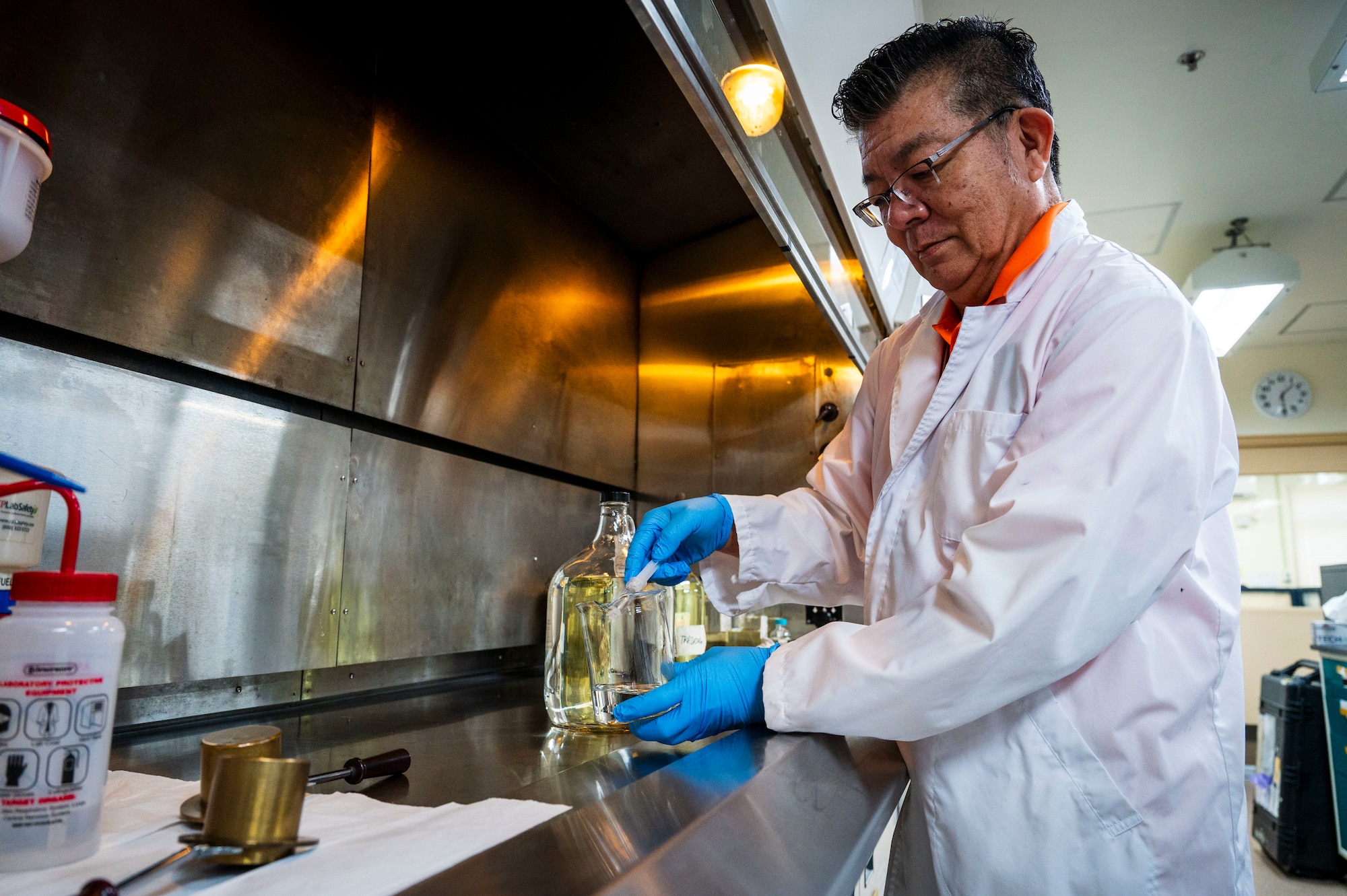 Atsushi Matsuda, Defense Logistics Agency Energy Okinawa physical science technician, extracts JP-8 fuel under a fume hood during testing near Kadena Air Base.