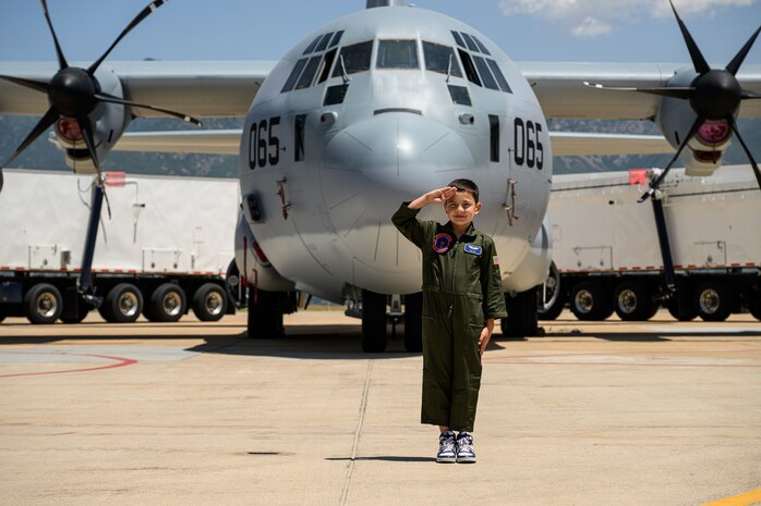 Dylan renders a salute in front of a C-130 Hercules aircraft.