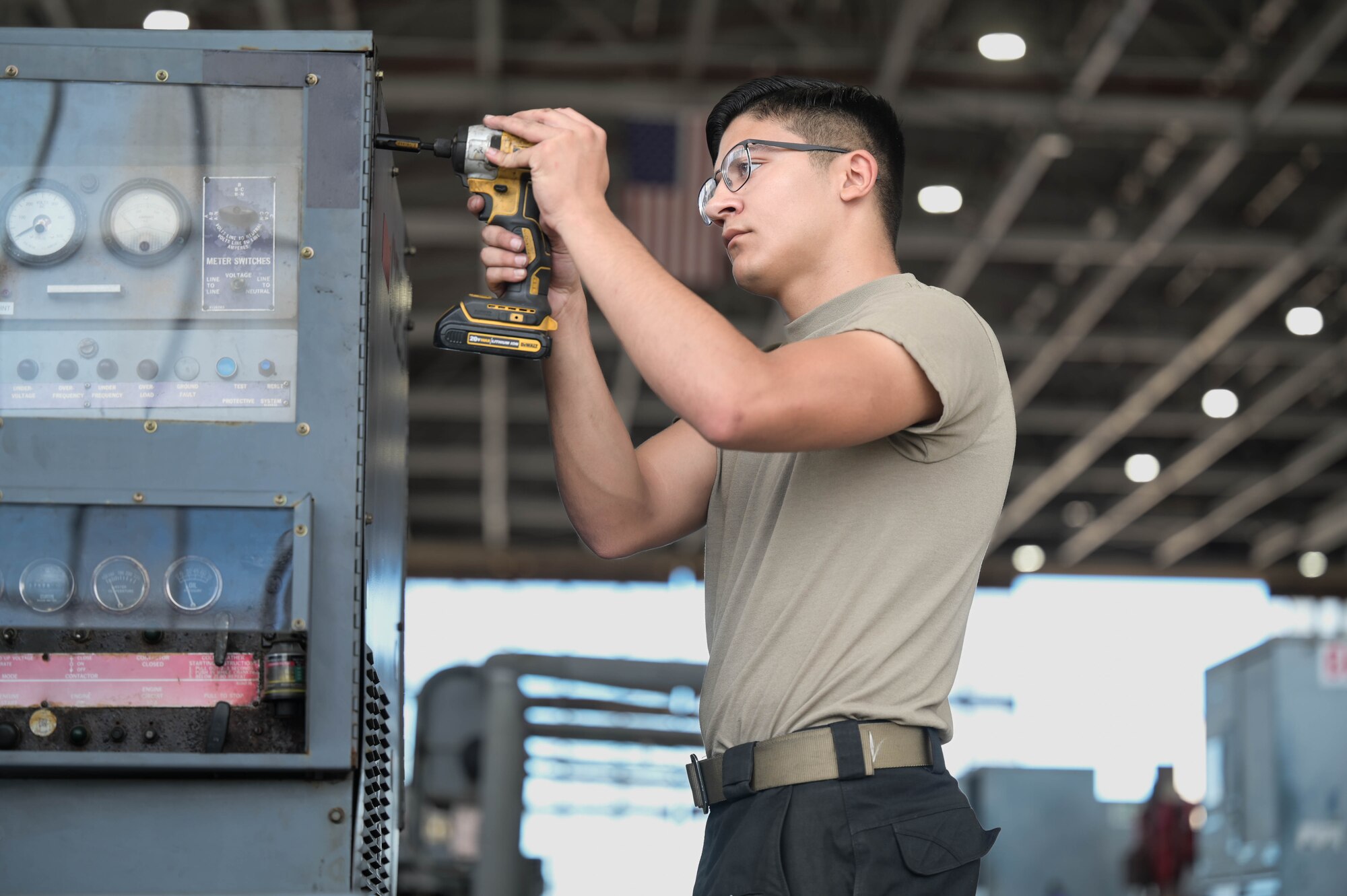 Airman using a drill on a generator.