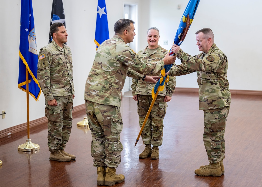 Incoming commander for the Defense Logistics Agency’s U.S. Central Command and U.S. Special Operations region Army Col. Edward Runyan accepts the flag from DLA Director of Logistics Operations Air Force Maj. Gen. David Sanford