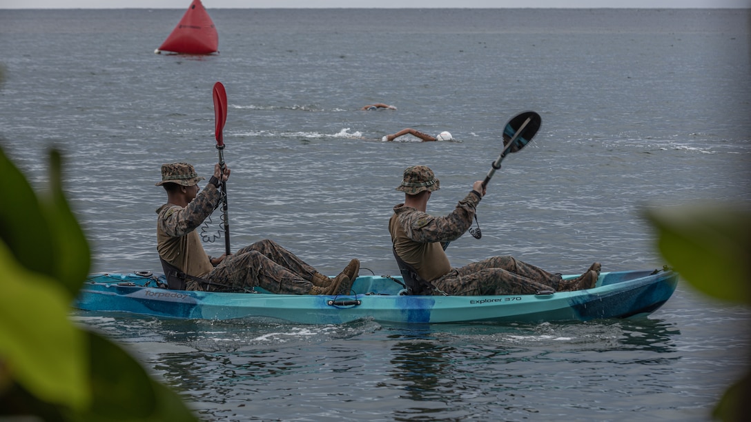 U.S. Marine Corps Sgt. Johnny Fox, right, a combat engineer, and Cpl. Ryan Ramsammy, a combat photographer, both with Combat Logistics Battalion 15, Combat Logistics Regiment 17, 1st Marine Logistics Group, monitor triathlon participants to provide assistance if needed and ensure the well-being of swimmers in the triathlon time trial held in preparation for the Pacific Mini Games during Koa Moana 25 in Ngiwal, Palau, June 21, 2025.