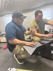 Vladimir Sequera, left, a logistics assistance representative with U.S. Army Medical Logistics Command, supports a member of the 512th Field Hospital, based at Kaiserslautern, Germany, and part of the 519th Hospital Center, during the hospital exercise portion of DEFENDER 2025 in Lithuania.
